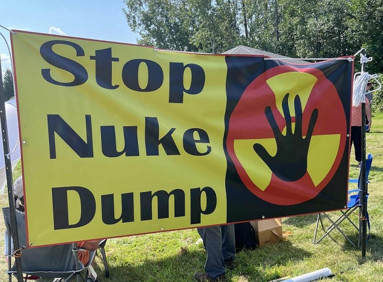 "stop nuke dump" sign with six-fingered hand